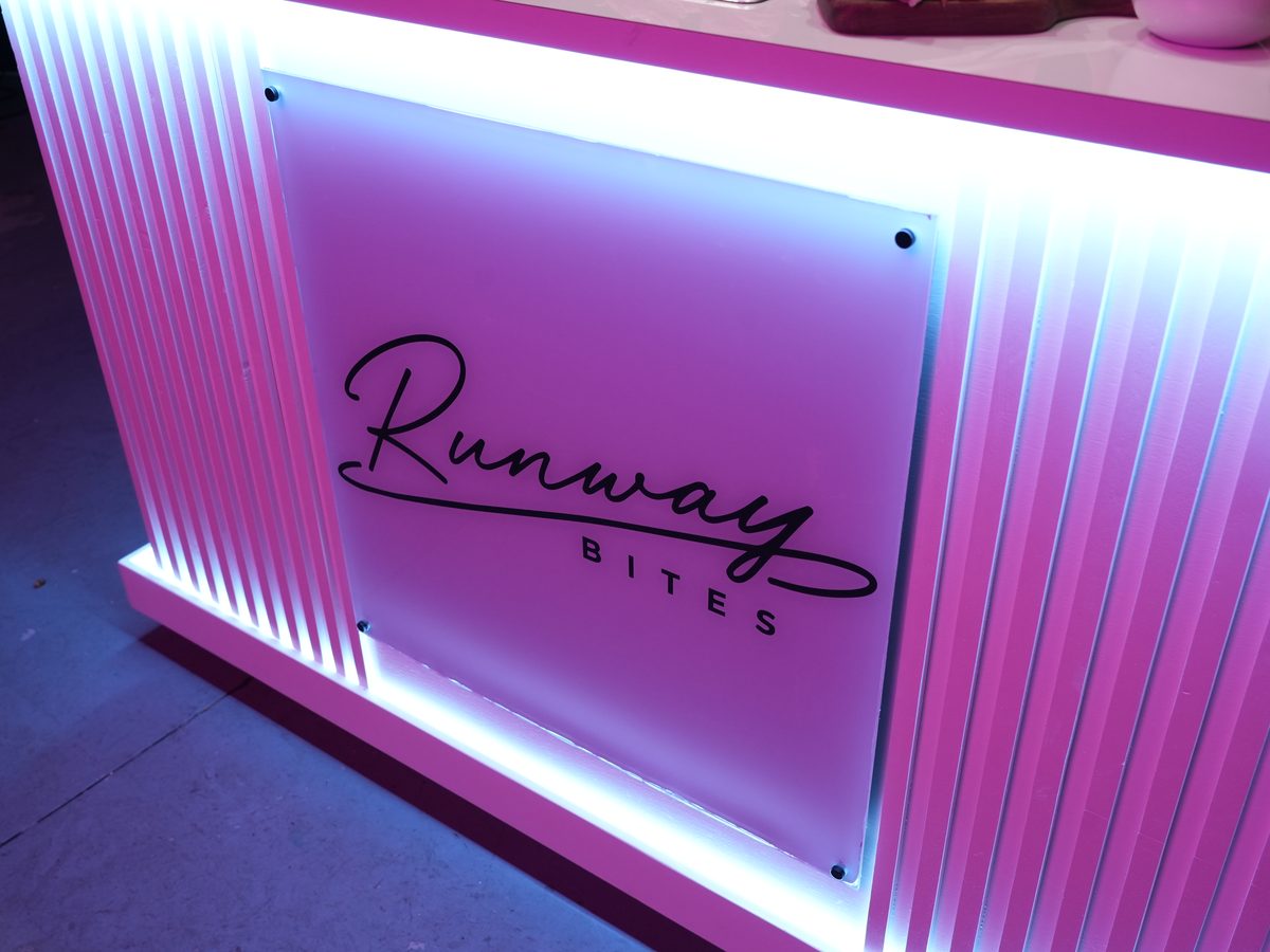 The illuminated Runway Bites bar signage in neon pink